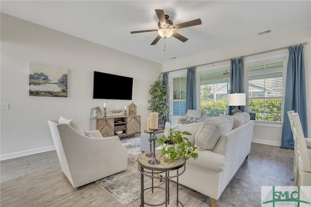 living room featuring wood finished floors, visible vents, and baseboards