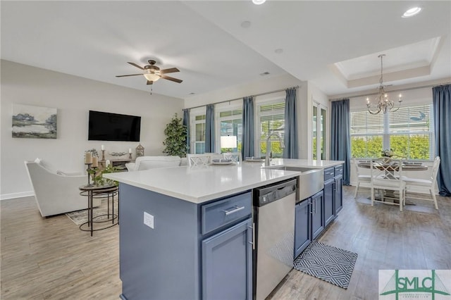 kitchen with dishwasher, light wood-type flooring, a tray ceiling, a wealth of natural light, and a sink