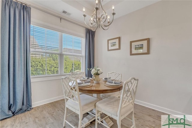 dining space with a notable chandelier, visible vents, baseboards, and wood finished floors