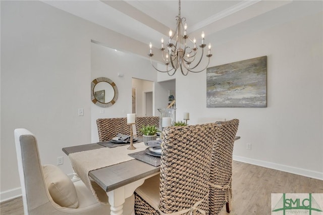 dining room with baseboards, a tray ceiling, and light wood-style floors