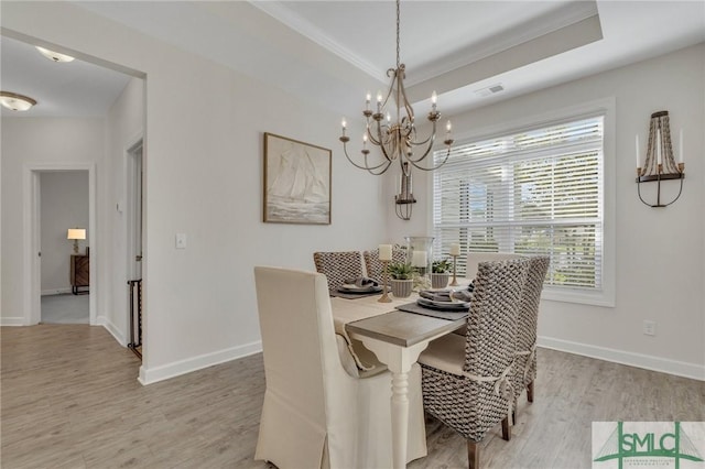 dining space featuring visible vents, baseboards, light wood-type flooring, and a tray ceiling