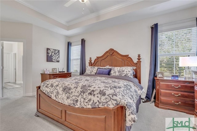 bedroom featuring ornamental molding, a tray ceiling, baseboards, light colored carpet, and ceiling fan