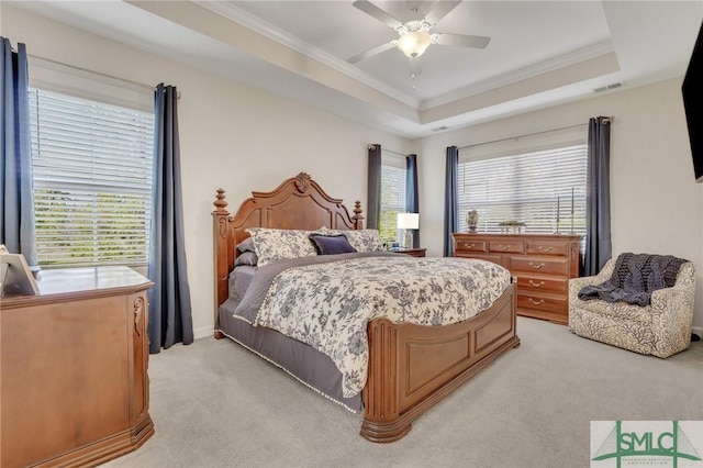 bedroom featuring visible vents, light colored carpet, a raised ceiling, and ornamental molding