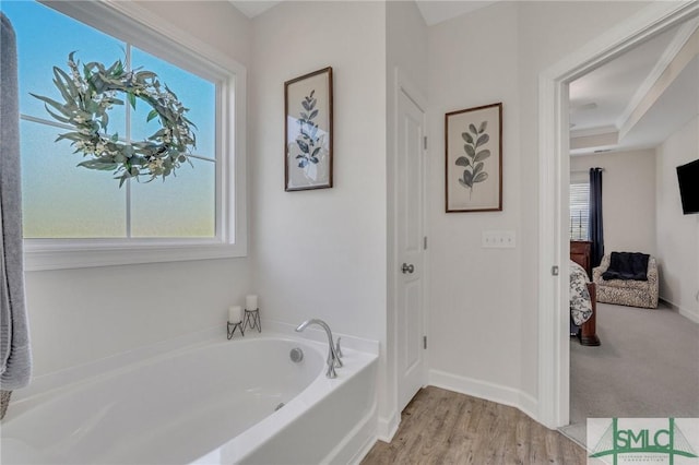 full bathroom featuring wood finished floors, connected bathroom, baseboards, and a bath