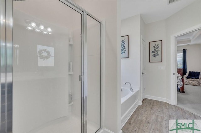 bathroom featuring a bath, connected bathroom, a shower stall, and wood finished floors