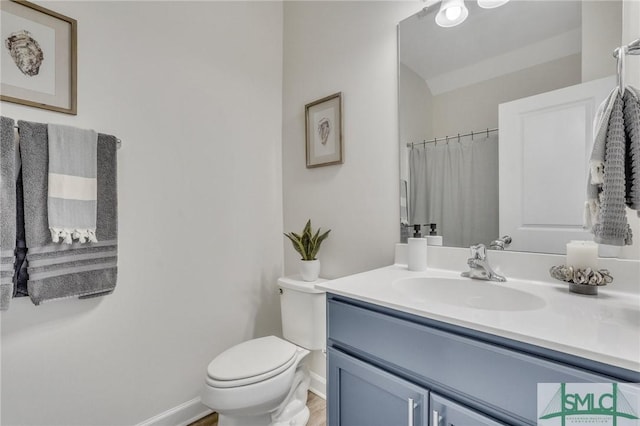 bathroom featuring baseboards, toilet, and vanity