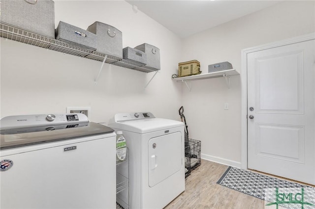 laundry area featuring laundry area, light wood-style floors, baseboards, and washing machine and clothes dryer