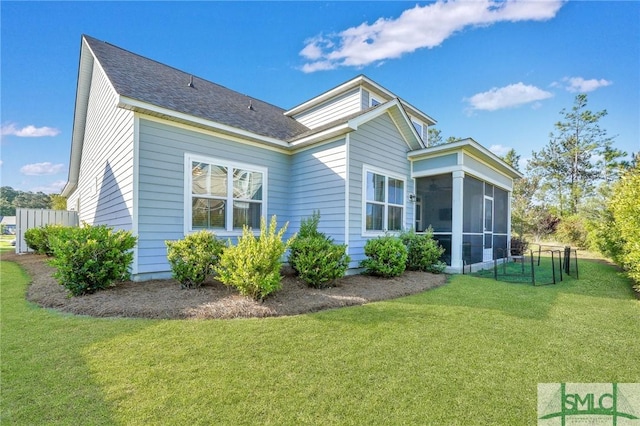 view of side of property featuring a lawn, roof with shingles, and a sunroom