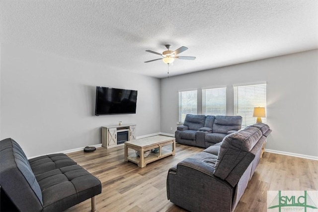 living room with a textured ceiling, baseboards, ceiling fan, and wood finished floors