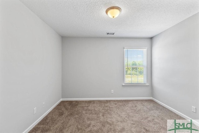 empty room featuring a textured ceiling, carpet, visible vents, and baseboards