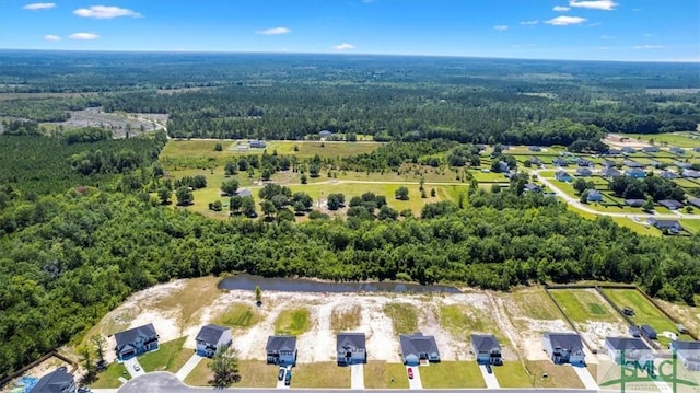 drone / aerial view with a wooded view and a water view