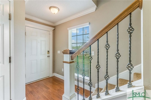 entryway featuring stairway, ornamental molding, baseboards, and wood finished floors