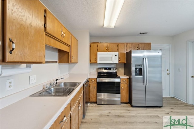 kitchen with visible vents, light countertops, appliances with stainless steel finishes, light wood-style floors, and a sink