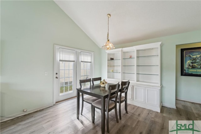 dining room with a chandelier, lofted ceiling, and wood finished floors