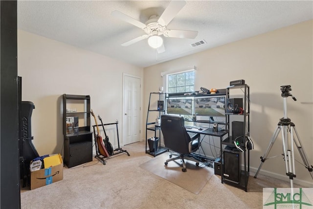 carpeted office space featuring visible vents, baseboards, a textured ceiling, and a ceiling fan