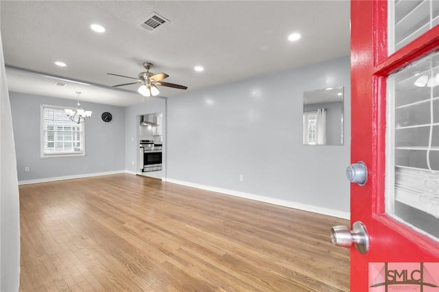 unfurnished living room with wood finished floors, visible vents, baseboards, recessed lighting, and ceiling fan with notable chandelier