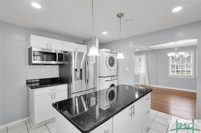 kitchen featuring white cabinetry, stacked washer / dryer, light tile patterned floors, and appliances with stainless steel finishes