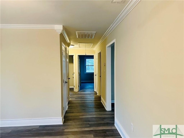 hall with visible vents, dark wood-type flooring, crown molding, baseboards, and attic access