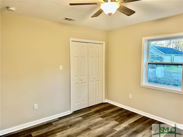 unfurnished bedroom with visible vents, baseboards, a closet, and dark wood finished floors