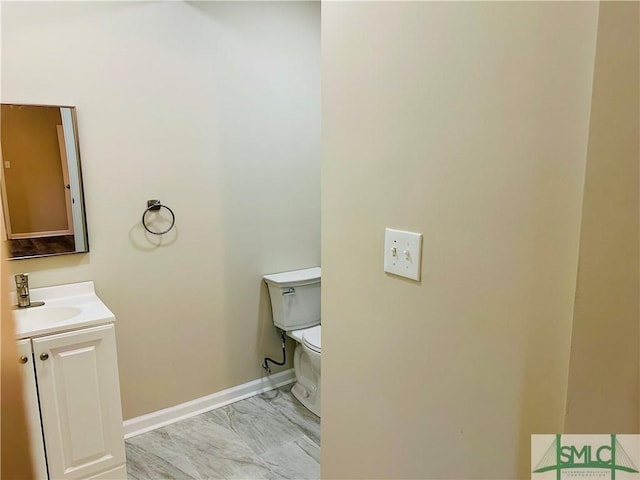 bathroom with toilet, vanity, and baseboards