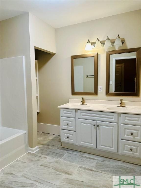 full bathroom with a sink, baseboards, a tub to relax in, and double vanity