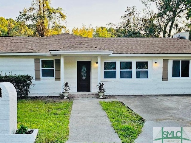 single story home featuring brick siding and roof with shingles