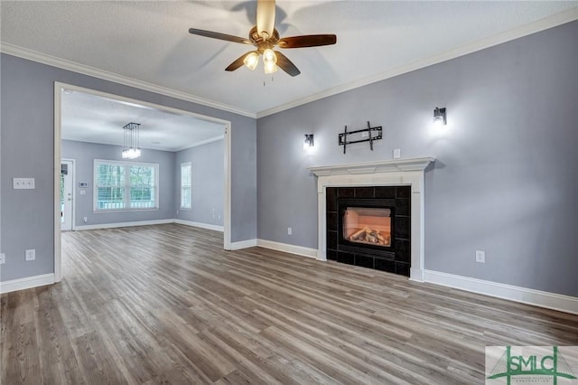 unfurnished living room with a fireplace, crown molding, baseboards, and wood finished floors