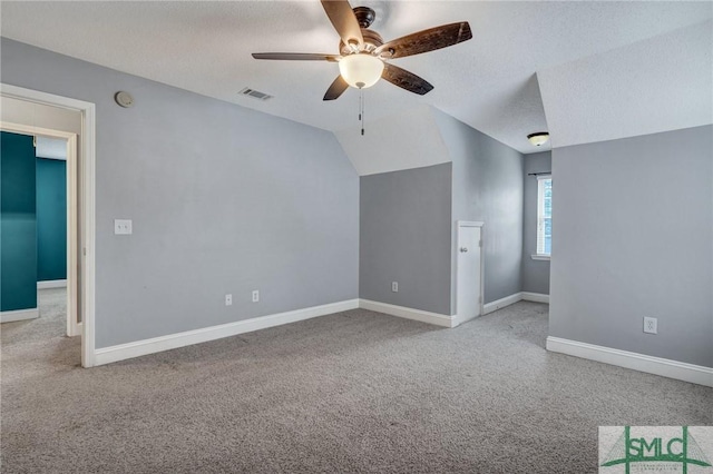 interior space featuring lofted ceiling, visible vents, carpet floors, and a textured ceiling