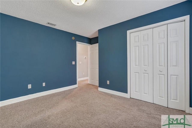 unfurnished bedroom featuring visible vents, carpet floors, a textured ceiling, and a closet