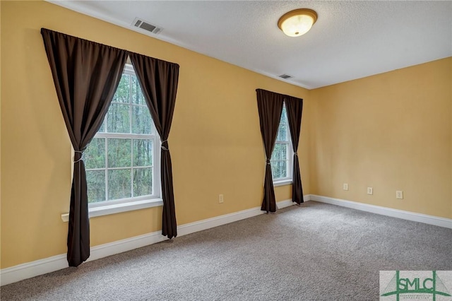 carpeted empty room featuring visible vents, a textured ceiling, and baseboards