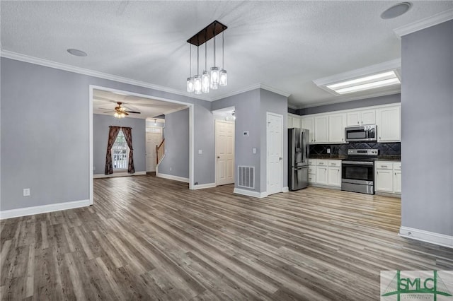 kitchen featuring visible vents, dark countertops, open floor plan, white cabinetry, and appliances with stainless steel finishes