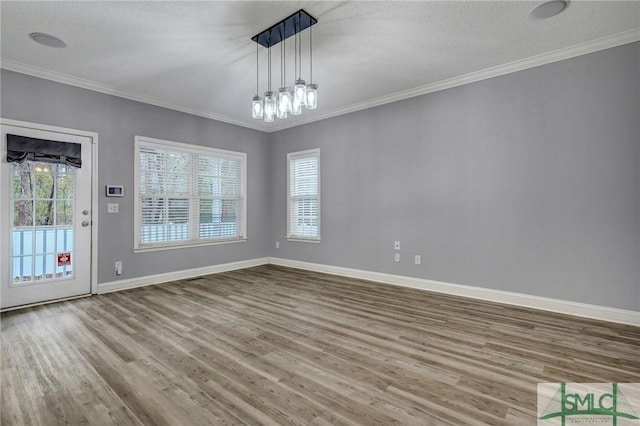 unfurnished dining area with a notable chandelier, crown molding, baseboards, and wood finished floors