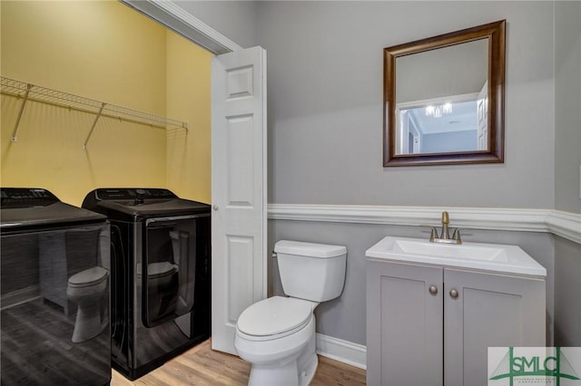 bathroom with washer and dryer, toilet, vanity, and wood finished floors