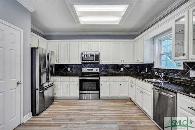 kitchen with a sink, stainless steel appliances, white cabinets, and crown molding