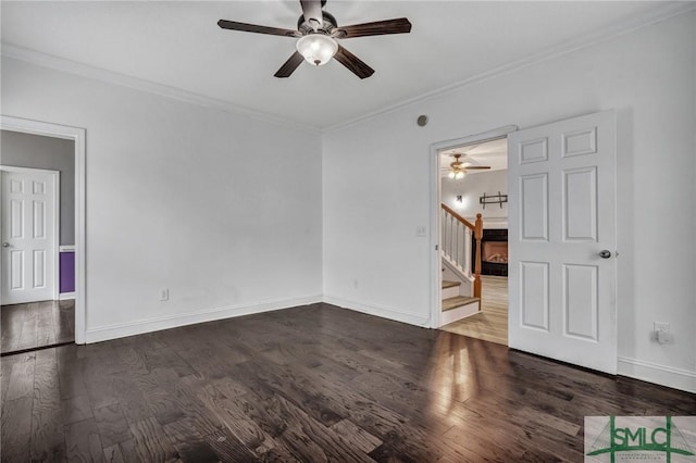 spare room with ornamental molding, stairs, baseboards, and dark wood-style flooring