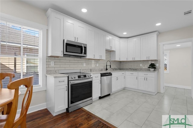 kitchen with visible vents, appliances with stainless steel finishes, white cabinetry, and decorative backsplash