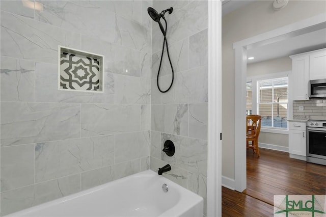 full bathroom with baseboards, wood finished floors, and shower / washtub combination