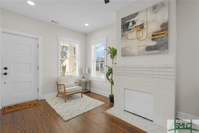 sitting room with visible vents, baseboards, recessed lighting, a fireplace, and wood finished floors