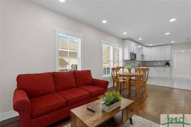 living room with recessed lighting, light wood-type flooring, and baseboards