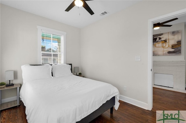 bedroom featuring a ceiling fan, wood finished floors, visible vents, and baseboards