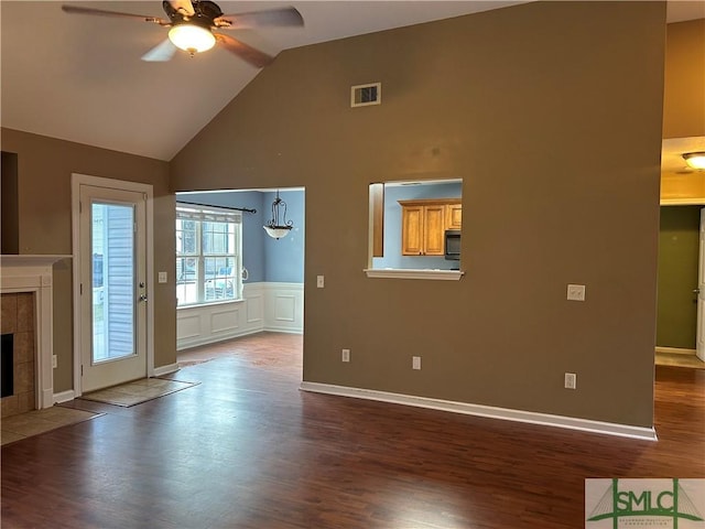 unfurnished living room with a ceiling fan, visible vents, high vaulted ceiling, dark wood-style flooring, and a tiled fireplace