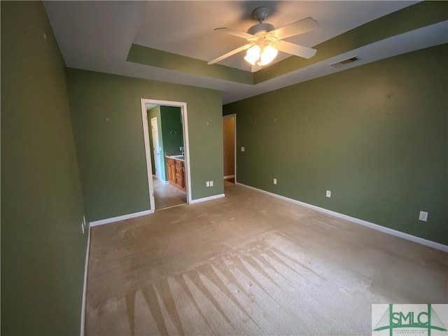 unfurnished bedroom featuring visible vents, a raised ceiling, carpet, baseboards, and ceiling fan