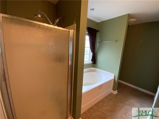 full bath featuring a shower stall, a garden tub, baseboards, and tile patterned floors