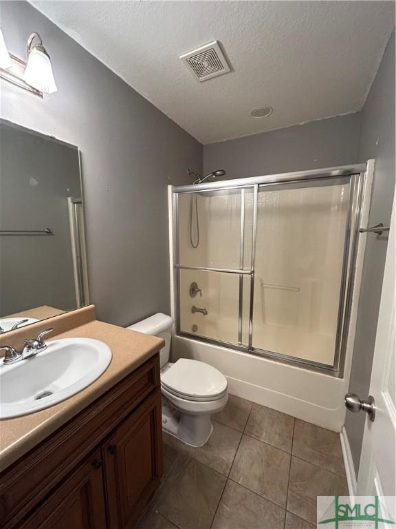 full bathroom with visible vents, toilet, vanity, shower / bath combination with glass door, and a textured ceiling