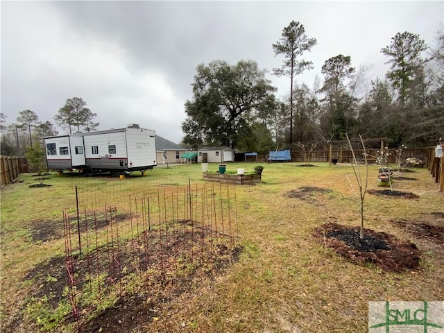 view of yard featuring an outbuilding, a storage unit, and fence