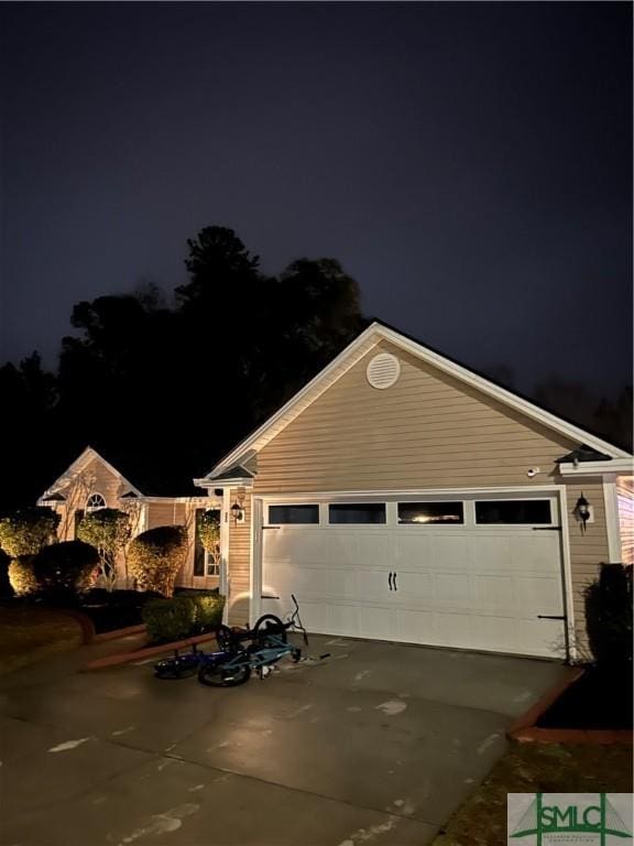 view of front of home with an outbuilding, concrete driveway, and an attached garage