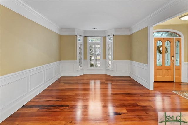 entryway featuring a wainscoted wall, wood finished floors, and crown molding