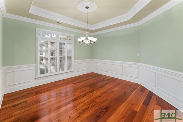 unfurnished room with visible vents, a tray ceiling, wainscoting, a notable chandelier, and dark wood-style flooring