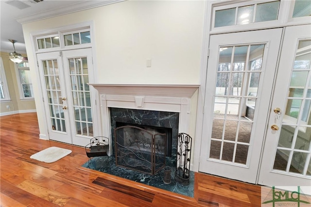 details with french doors, a fireplace, crown molding, and wood finished floors