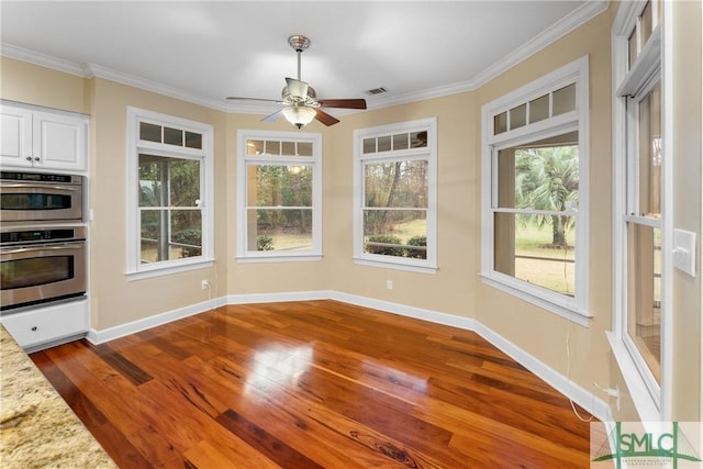 unfurnished dining area with dark wood-type flooring, plenty of natural light, and ornamental molding